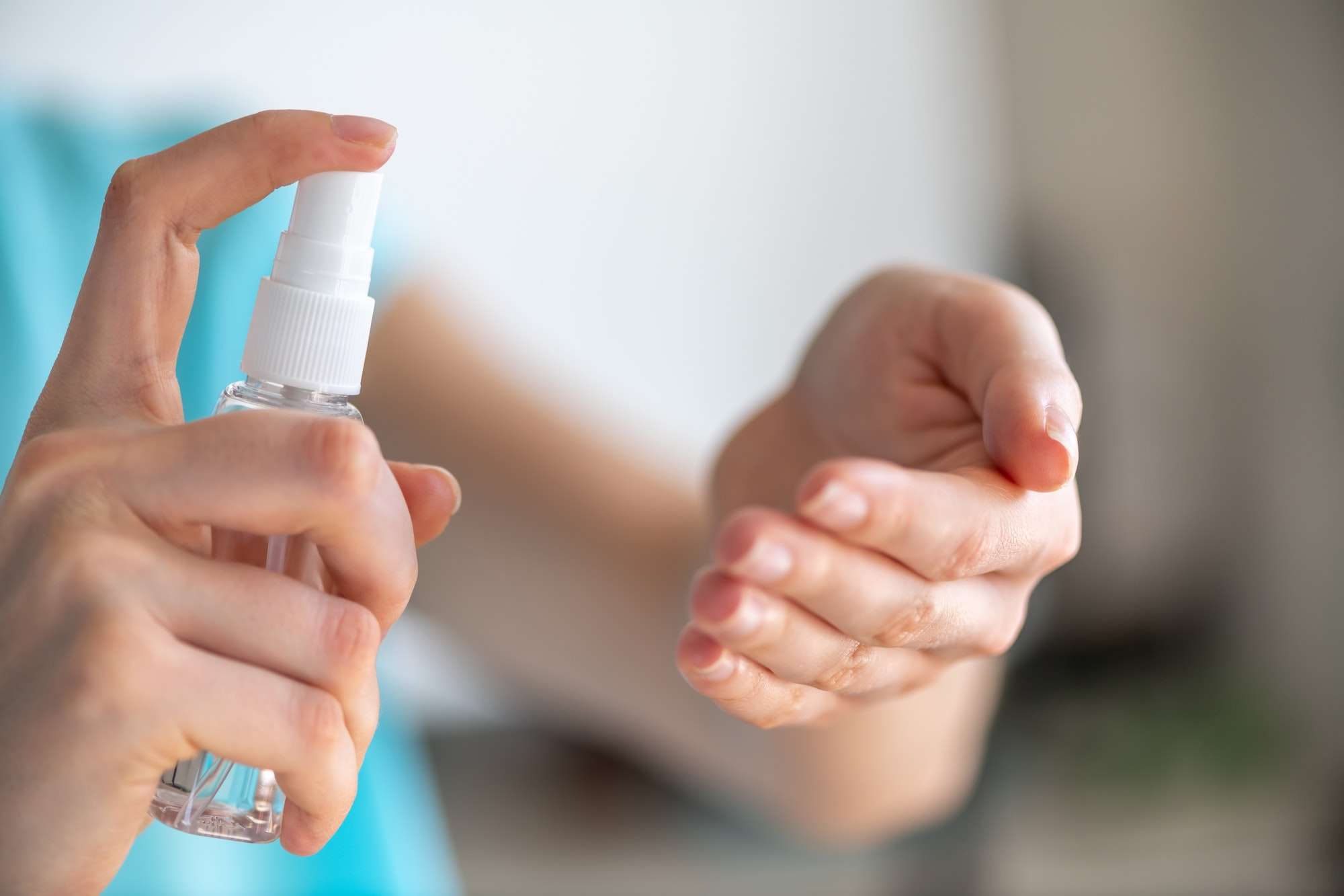 Girl applying spray disinfectant alcohol product on hand